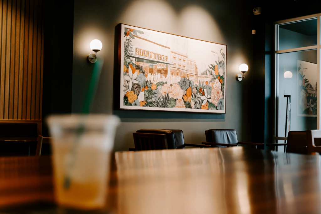 Starbucks Drink sitting on table with beautiful flower artwork in the background.